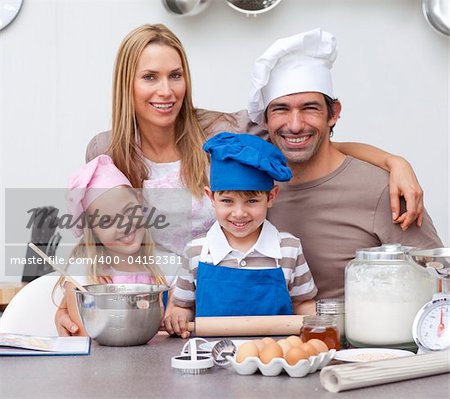 Smiling parents helping children baking cookies in the kitchen