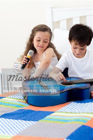 Brother and sister having fun with a guitar in the bedroom