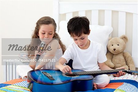 Siblings singing and playing guitar in the bedroom