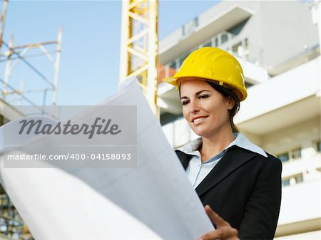 female engineer looking at blueprints in construction site
