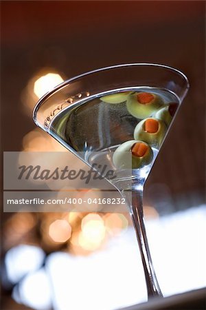 Martini glass seen from below with the olives being reflected off of the top of the drink. Vertical shot.