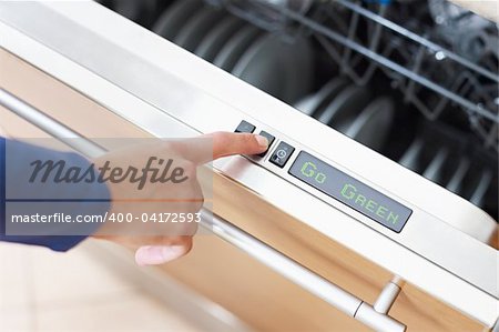 Go Green concept. Close up of woman using dishwasher in energy saver mode. Horizontal shape