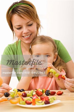 Fruits on stick - woman and little girl preparing healthy snack