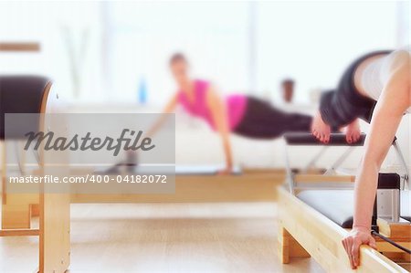Pilates apparatus in use by two people, soft focus