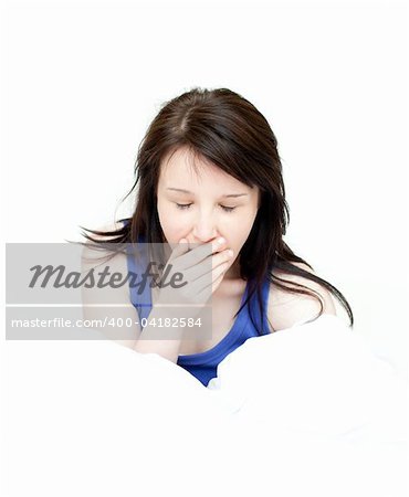 Charming woman yawning sitting on her bed at home
