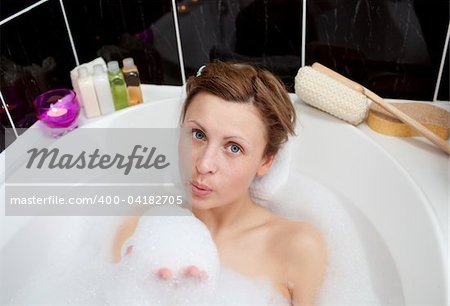 Attractive woman playing in a bubble bath at home