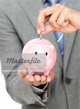 Close-up of a businessman saving money in a piggy-bank against a white background