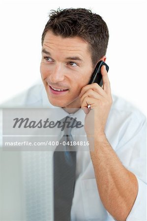 Smiling businessman on phone working at a computer
