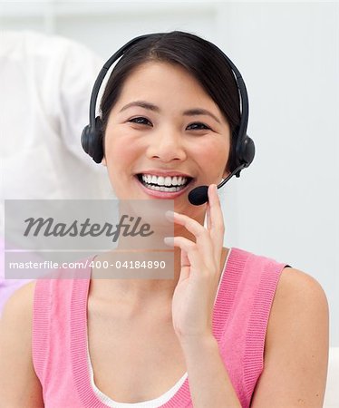 Positive Asian businesswoman talking on headset in the office