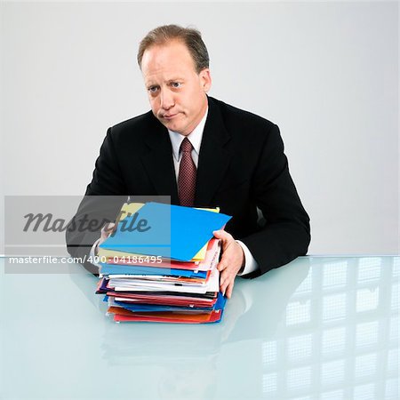 Caucasian middle aged businessman with stack of folders.
