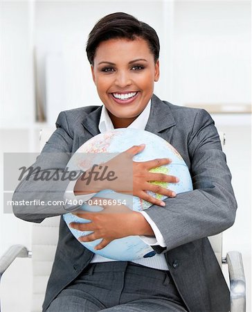 Charismatic businesswoman holding a terrestrial globe in the office