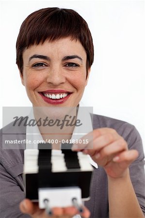 Positive businesswoman consulting a business card holder against a white background