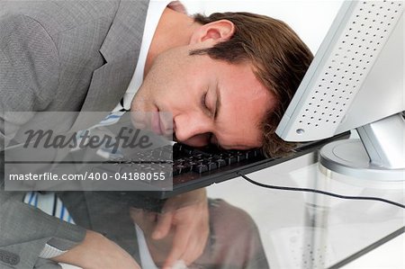 Close-ep of a tired businessman sleeping on his desk against a white background