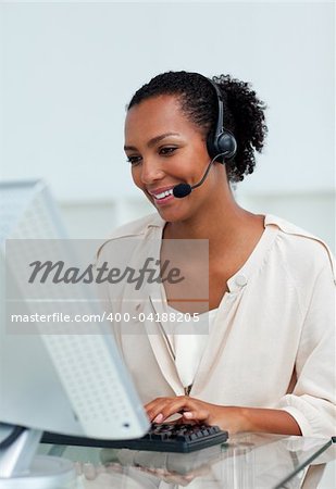 Cheerful businesswoman with headset on working at a computer in a call-center
