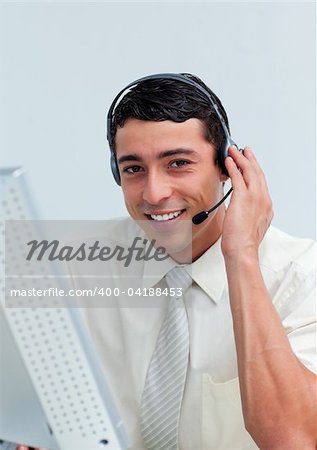 Assertive businessman using headset working at a computer