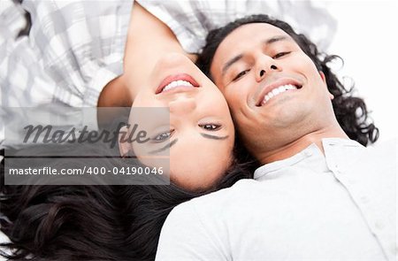 Laughing couple relaxing on the floor against a white background