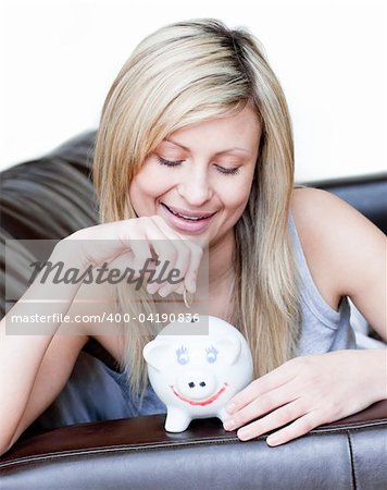 Radiant woman using a piggybank against a white background