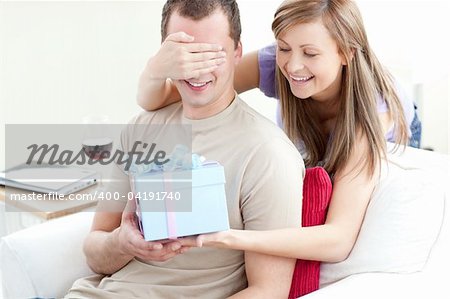Smiling woman giving a present to her boyfriend in the living-room