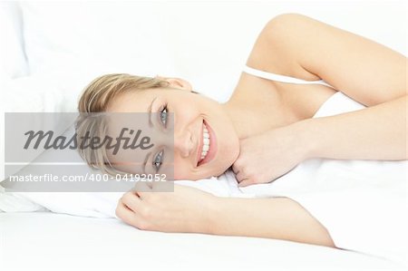 Jolly woman relaxing lying on a bed at home