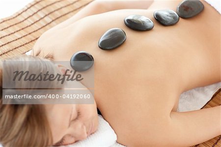 Bright woman lying on a massage table having a stone therapy