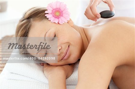 Portrait of a radiant woman having a flower on a massage table