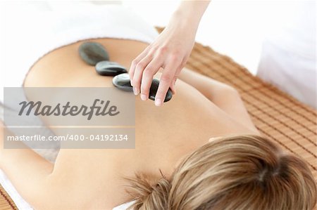 Radiant woman having a stone therapy against a white background