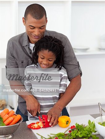 Attentive father helping his son cut vegetables in the kitchen