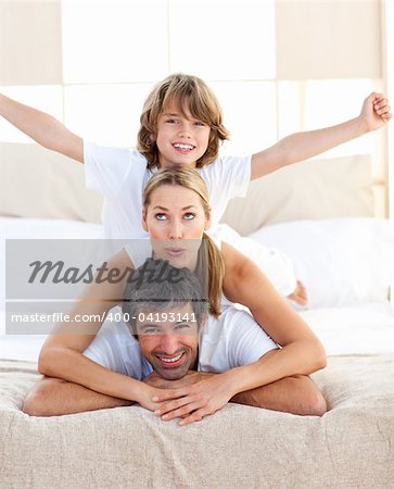 Cute child and his parents having fun lying on the bed