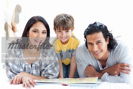 Happy family reading book together lying on the floor