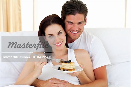 Jolly couple having breakfast lying in the bed