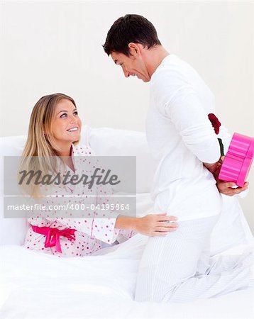 Lovely husband giving a present to his wife in the bedroom