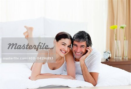 Portrait of a romantic couple embracing lying on their bed