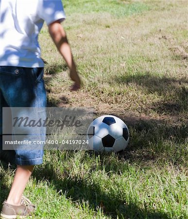 Little boy playing soccer in a park