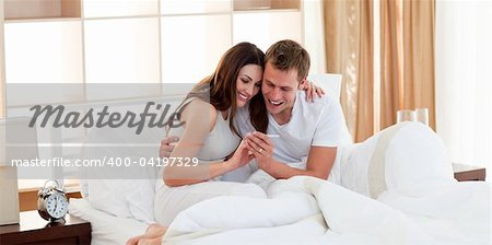 Attentive couple finding out results of a pregnancy test sitting on bed at home