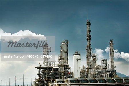 Oil refinery with smoke against moody sky