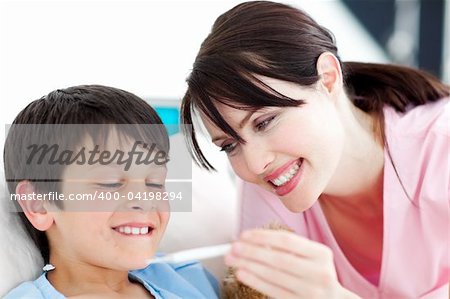 Smiling nurse and his patient looking at a thermometer in a hospital Smiling nurse and his patient looking at a thermometer in a hospital
