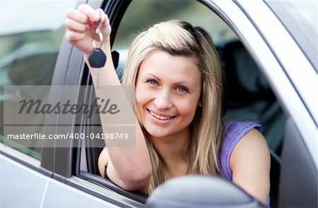 Portrait of an attractive young driver holding a key after bying a new car