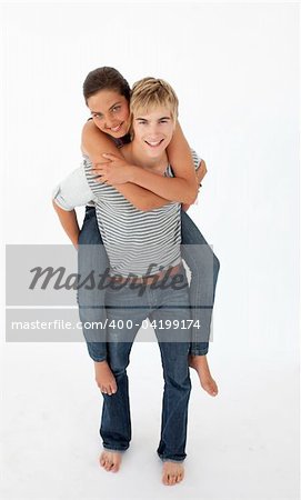 Young boy giving his girlfriend piggyback ride against white background