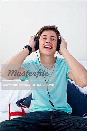 Teenager listening to the music in his bedroom with headphones at home