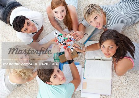 High angle of teenagers studying Science on the floor in a house