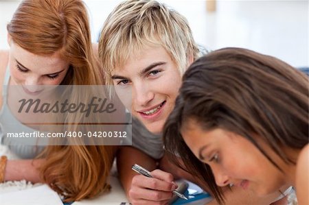 Teenagers doing homework on the floor at home