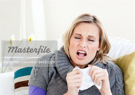 Young woman sneezes on a sofa