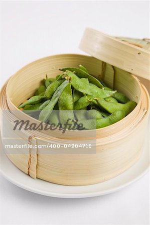 Edamame soybeans served warm with salt in bamboo steamer basket