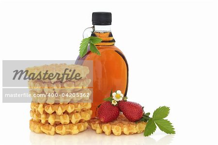 Waffle stack and maple syrup with strawberry fruit and flower blossom with leaf sprig,  isolated over white background with copy space.