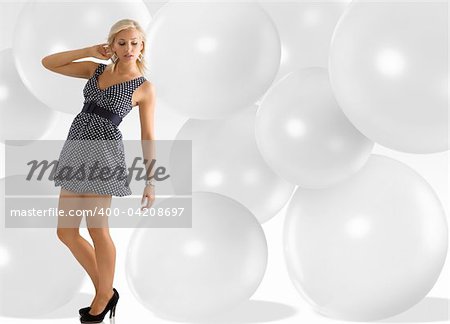 blond young woman wearing blue polka dot dress jewellery and taking pose