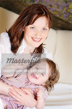 Beautiful mother hugs her 9-months baby-daughter and smiling closeup