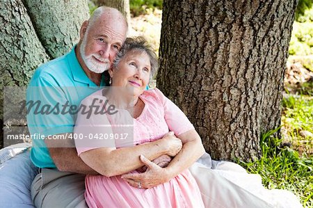 Nostalgic senior couple sitting outdoors and remembering.