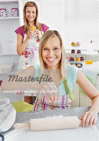 Animated female friends baking muffins in the kitchen smiling at the camera