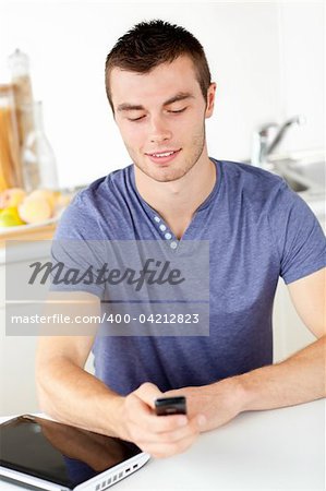 Positive young man sending a text in the living-room at home