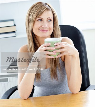 Relaxed businesswoman holding a cup of coffee in her office at her desk